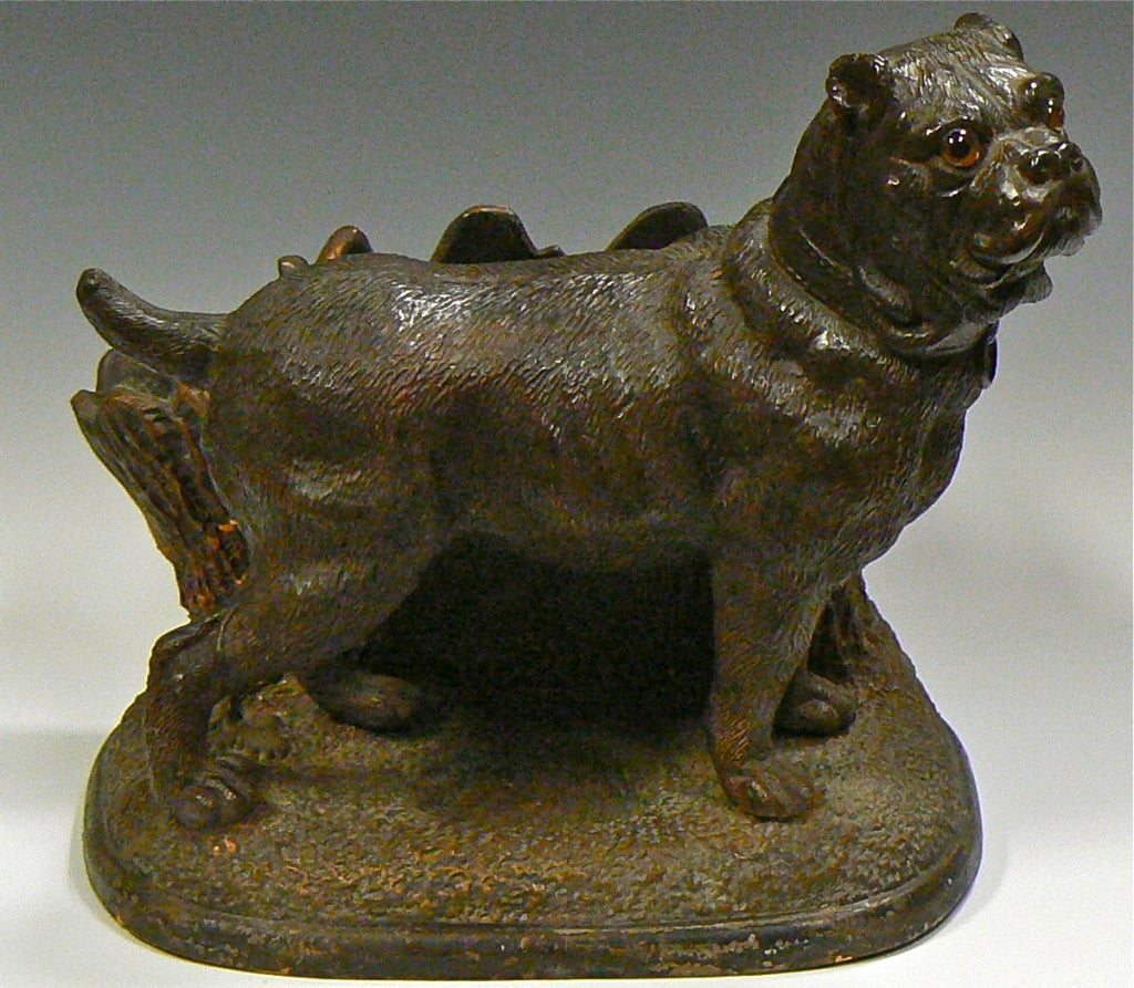 A rare standing Mastiff Bulldog figurine with glass eyes having a cigar receptacle and match holder. Made of a terra cotta clay, it  dates to about 1890. It is signed with the initials 