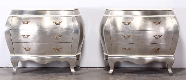 A pair of Italian style silver leaf Bombay chests with faux cream painted tessellated bone accent border.