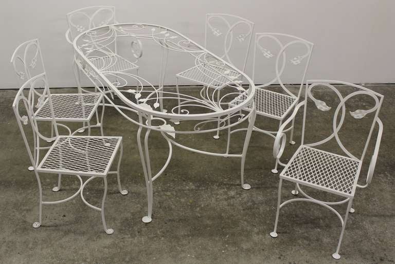 Ornate Salterini wrought iron chairs and table newly powder coated white. There are two arm chairs and four side chairs.
