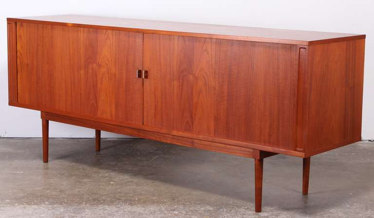 A beautiful Danish Teak credenza or sideboard by Lovig. Paper label on back side. Great detailed handles made of teak and steel. Lots of drawers, compartments and shelving. Back side grain is as nice as the front of cabinet.
