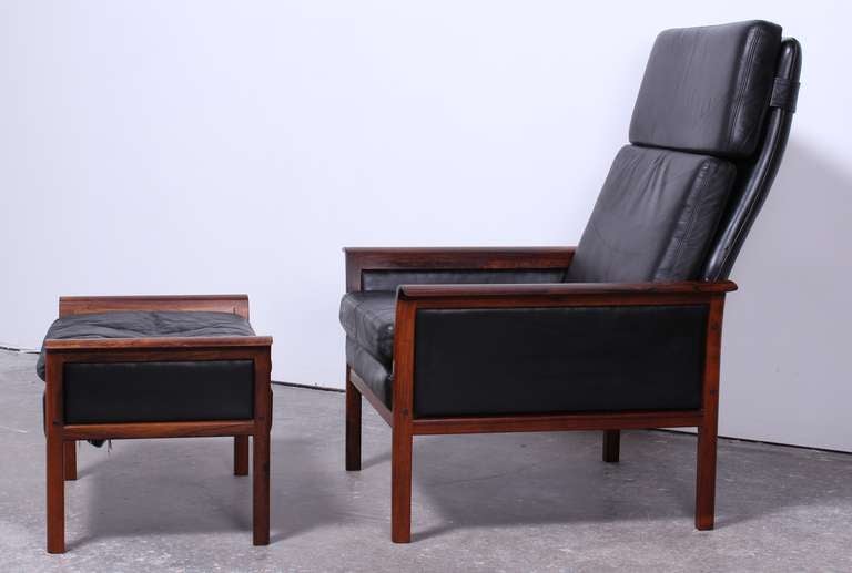 Hans Olsen rosewood and black leather armchair and ottoman. Beautiful rosewood grain with feather down cushions and soft leather upholstery.