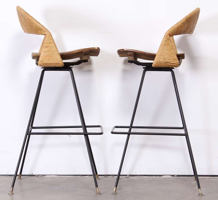 A modernist set of 1950's wrought iron bar stools with rush back and slatted seats by Arthur Umanoff.