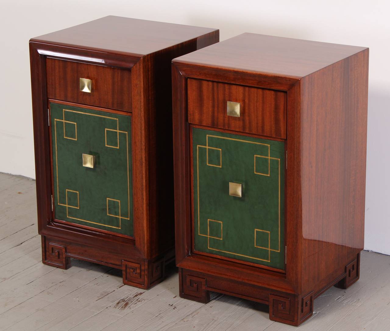 A luxurious pair of Hollywood Regency Grosfeld House style side tables in mahogany wood. Accented with hunter green leather and hand tooled gold leaf. Professionally refinished by Alternative Furnishings Inc. This pair of bedside tables can be