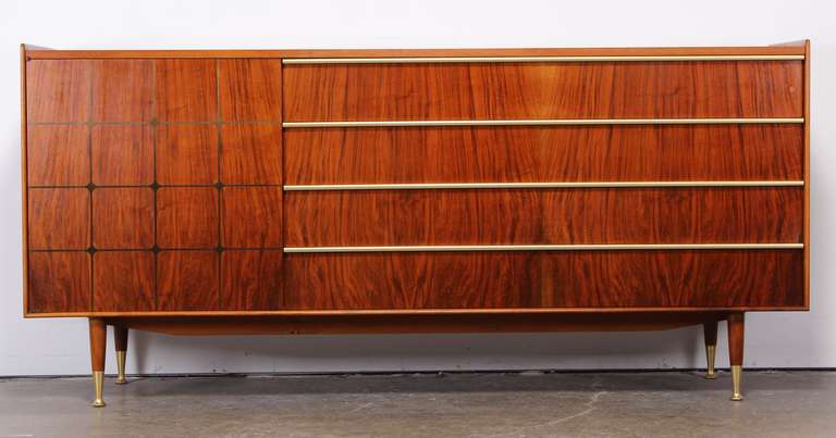A gorgeous Mid-Century Modern rosewood dresser or credenza by Edmond Spence. This piece features a patterned door with dark wood inlay, brass drawer pulls and feet. A very functional cabinet with one drawer on left side and shelving and four large