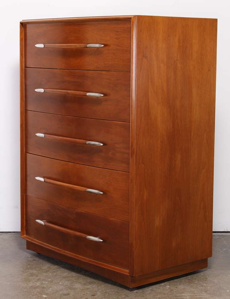 A tall chest of drawers by T.H. Robsjohn-Gibbings for Widdicomb Furniture Company. Sleek walnut modern design chest with silver plated drawer pulls.
