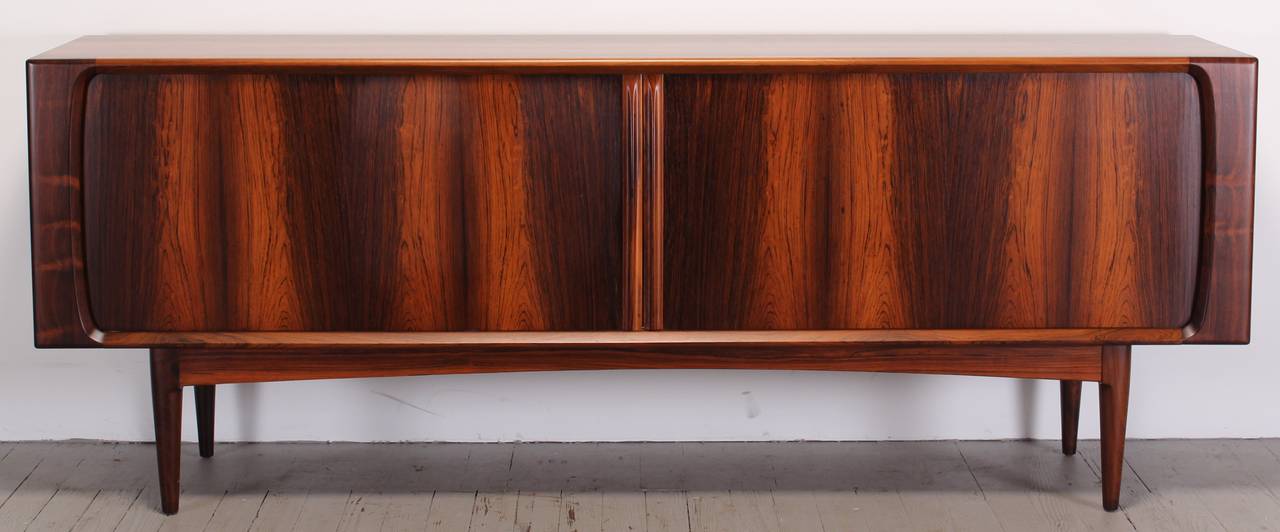 A Danish Bernhard Pedersen & Son rosewood credenza or sideboard. This Mid-Century Modern piece is in excellent condition with clean lines and beautiful rosewood grain pattern. The credenza has tambour doors and four drawers and two shelves for ample