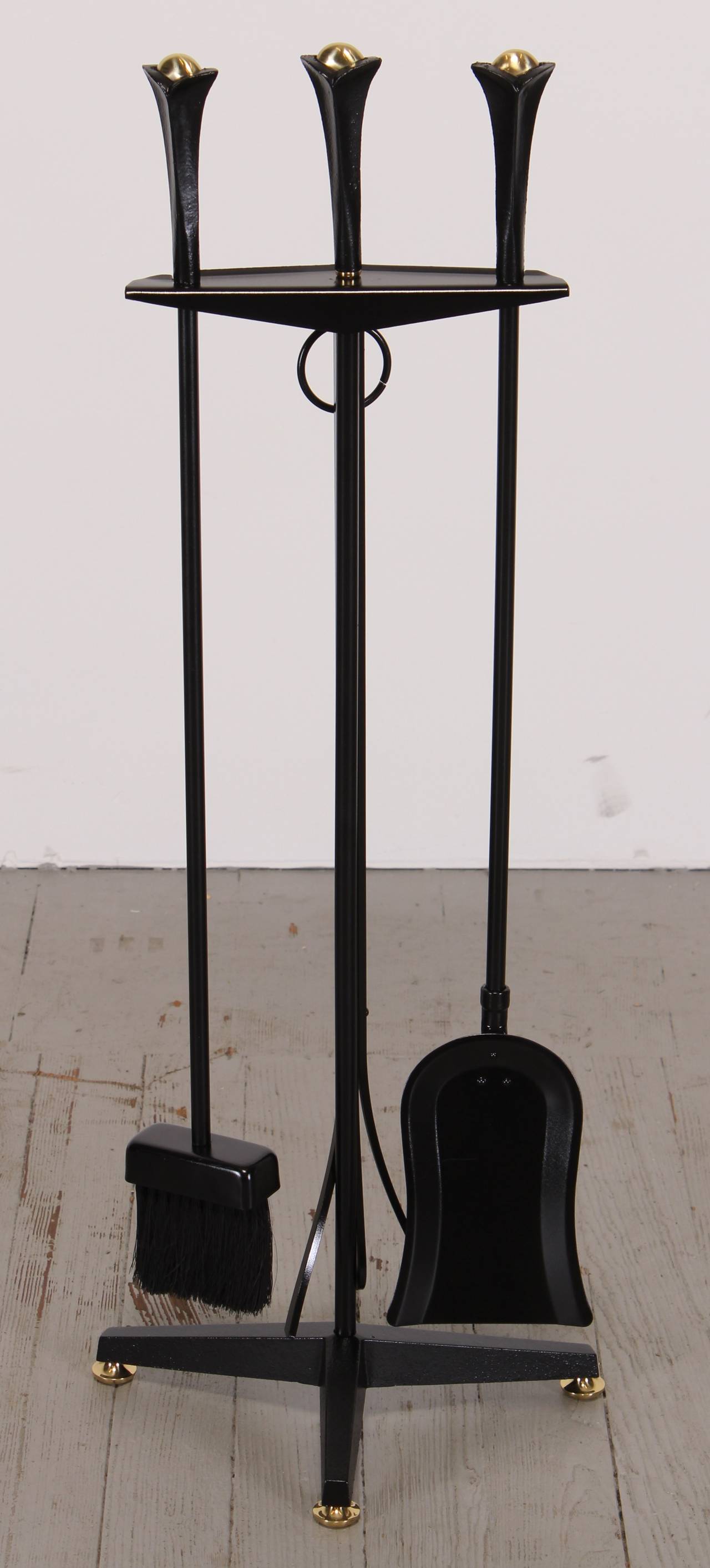 Pair of andirons and fireplace tools in cast wrought iron with brass detail designed by Donald Deskey for Bennett Co. The dimensions of andirons found below. The fireplace tools measure 32.50 H x 13 W x 7 D.