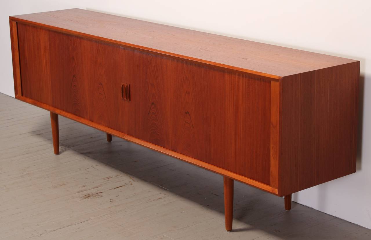 An excellent Scandinavian Danish teak credenza by Sven Aage Larsen for Faarup Mobelfabrik, 1960. Plenty of drawers and shelving for ample storage. Beautiful tambour doors with modernist carved pulls.