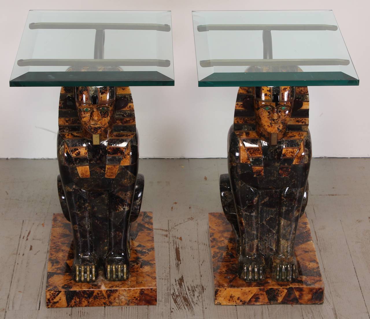 A unique and decorative pair of tessellated stone sphinx side tables or end tables by Maitland-Smith, 1980. These tables are accentuated with brass tails, inlaid brass accents, wooden claws and stone eyes. Small chips to corners of beveled glass as