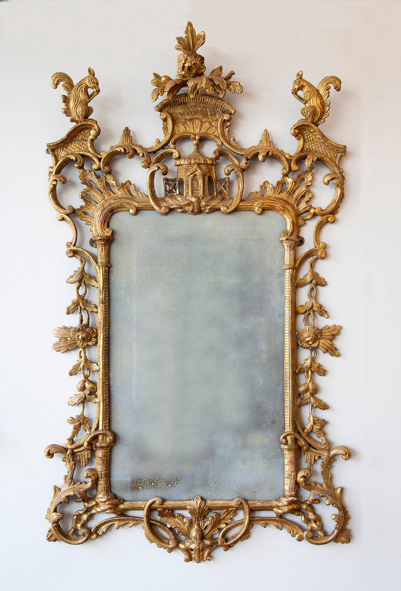 Large giltwood girandole mirror with two squirrels  over a pagoda. Verticle  rectangular plate and frame flanked by carved fretwork branches and vines with leaves and scrolled decoration centering a carved base. Circa late 18th century.