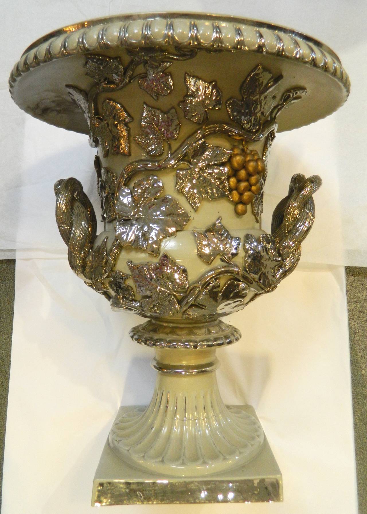 Greek Revival large stoneware urn with taupe ground and applied raised grapes and leaves with silver decoration, circa 1850s. The handles are twisted vines.
This is one of two urns being offered individually that are similar sizes and are great