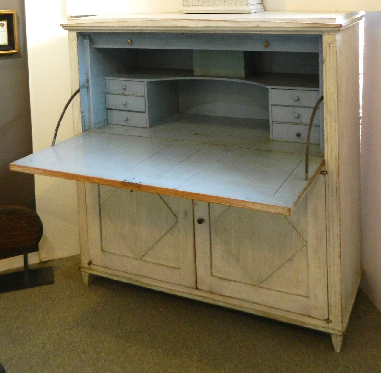 An early 19th century Swedish drop front desk and clock. It has an old painted surface with pale blue interior and a lower two-door cabinet with a single shelf. The clock is 50