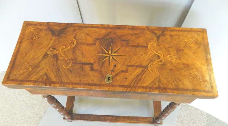 An 18th century antique marquetry decorated Italian flip top table with elaborate marquetry decoration on the top and turned leg.  It has an interior hidden compartment and swing out back legs. Great narrow size for difficult spots. Closed it is
