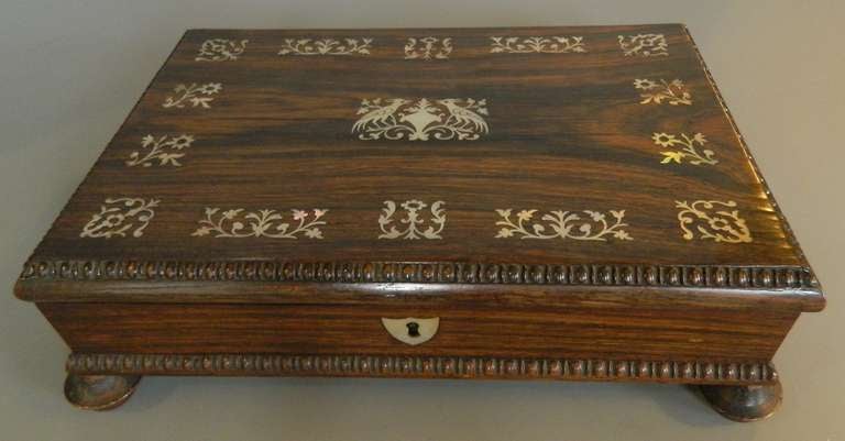 Rosewood games box made in England with mother of pearl inlay, lock with key, fitted with cards, games counters, cribbage board with pegs and dice.  Early 19th century.