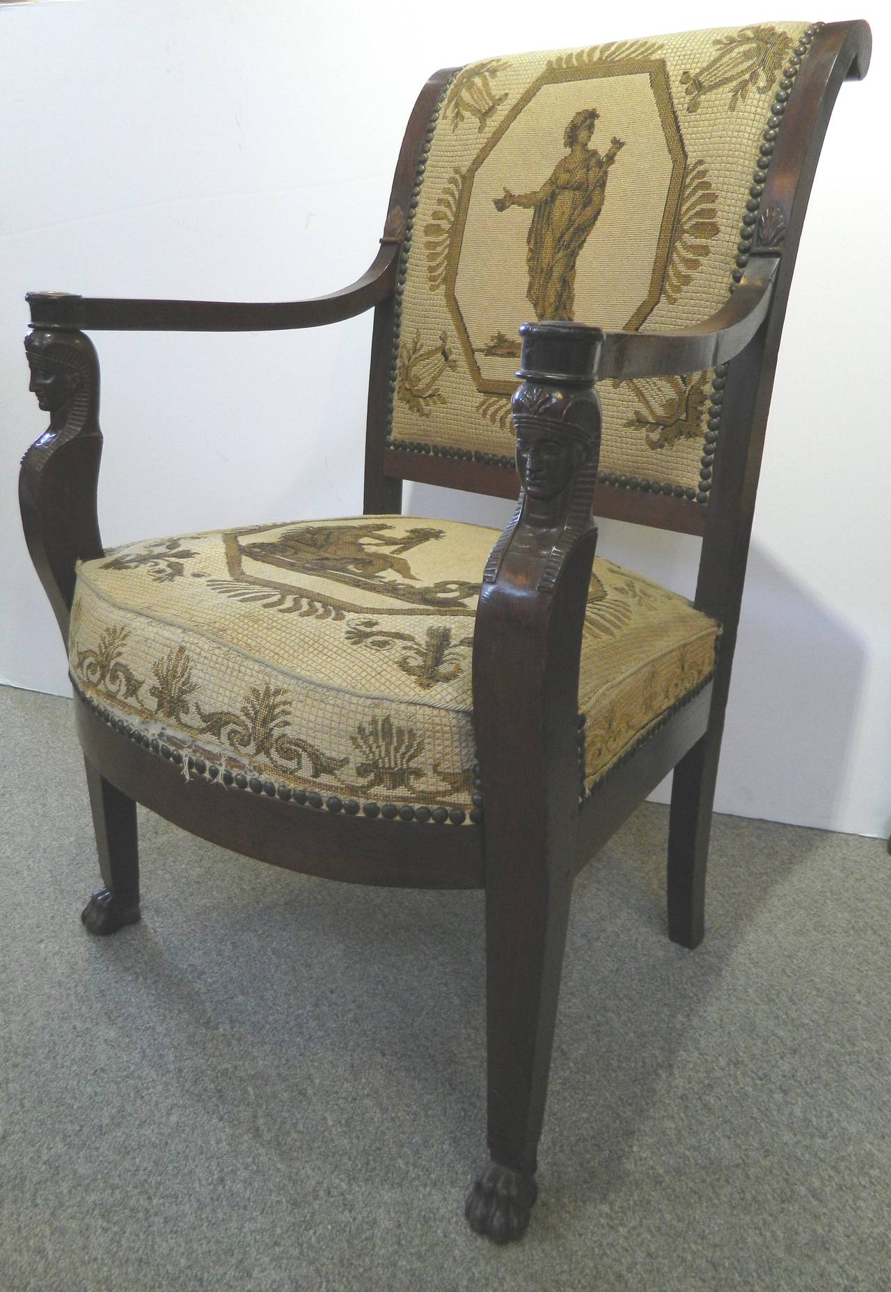 Great pair of mahogany Greek Revival armchairs with Spinx head supports  terminating in paw feet. The needlepoint upholstery is hand done and has some flaws.  Circa 1820 to 30.