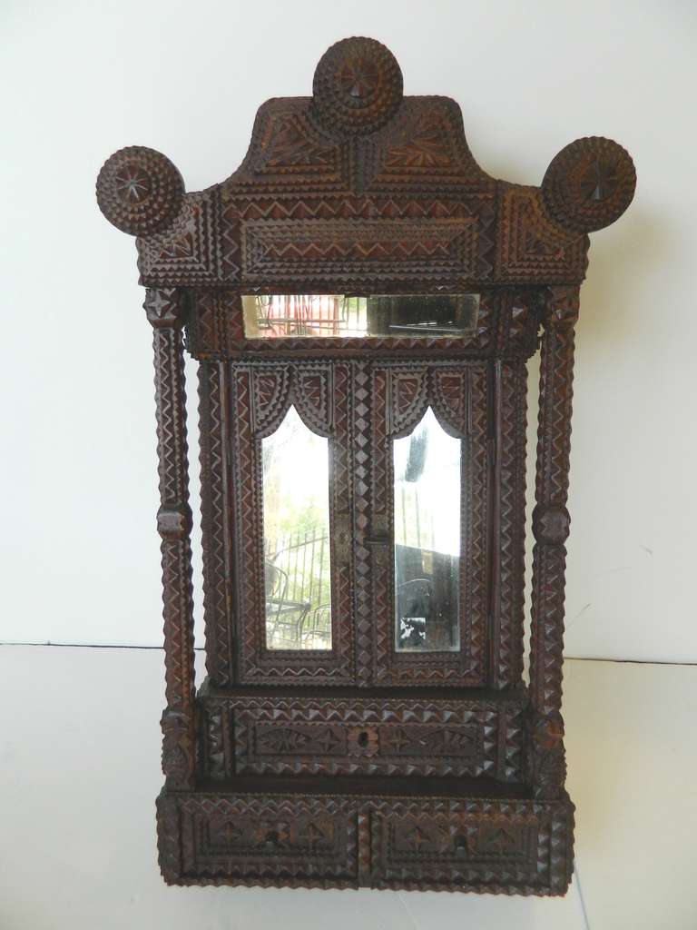 Fine antique Tramp Art cabinet or wardrobe with two mirrored cabinet doors and one inner shelf above two small drawers over one long drawer. This early twentieth century Folk Art form is chip carved. 
It is in very good condition.