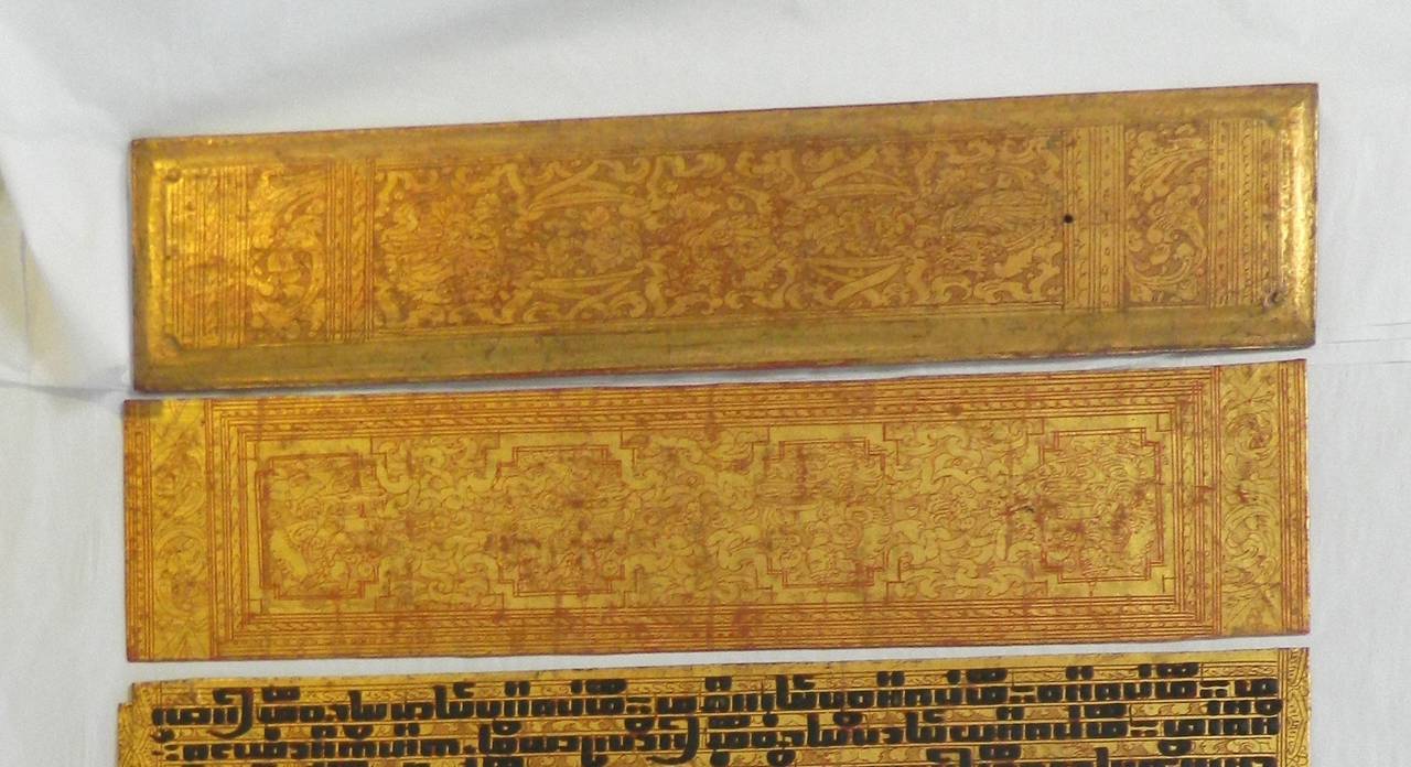 Antique Burmese Buddhist gilt and lacquer sutra manuscript done in the 19th century in Burma (Myanmar). This text is a rectangular shape with hand-painted intricate wood cover boards (red on the back) and sixteen pages or leaves with text on both