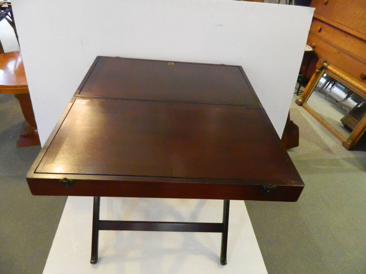 Antique mahogany folding desk with usable table top when opened. One side has a mirror and sectioned storage, the other a few sections. 
This desk is substantial enough to use as a table when opened.