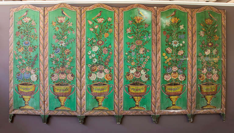 An 18th c. painted Italian screen made of six panels.  Each canvas  panel is painted with stylized flowers and urns and framed in wood.  The paint has rubbed off two of the panels leaving a white surface.