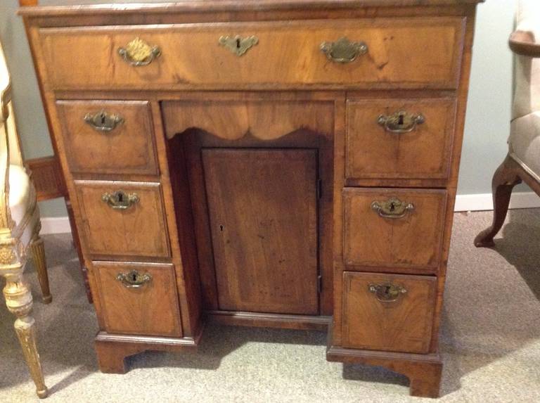 Antique English walnut kneehole desk with one top full drawer and six side drawers, all dovetailed. Center door conceals a shelf. It had nice inlay and old rich color to the wood. Probably late 18th century.