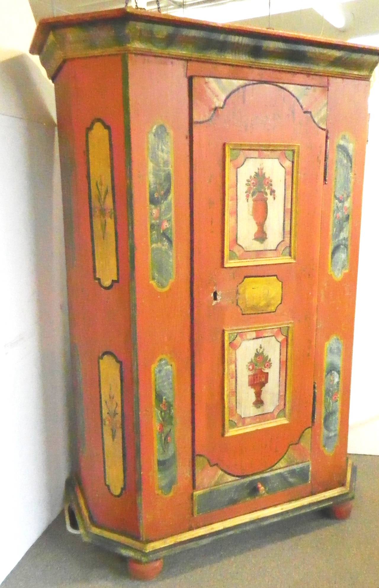 Charming peach color painted wardrobe with pots of flower panels on the door on bun feet. Between the flower panels is a date of 1720. There is an antique hand made key for the cabinet lock. The one cabinet door opens to a large space with two rows