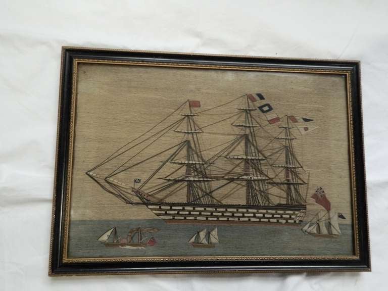 A sailor's woolwork picture of a 3 masted sailing ship, flying red ensign and other flags with attending boats in the foreground. Sailors woolworks, commonly known as ‘woolies’ or string pictures were produced from around 1840 until around World War