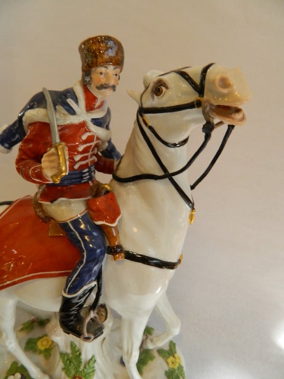 Meissen figurine of a soldier in uniform on horseback on a base with applied flowers.