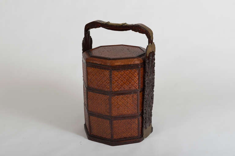 Comprised of three stacking lidded octagonal bamboo baskets set within a carved hardwood and brass stand.