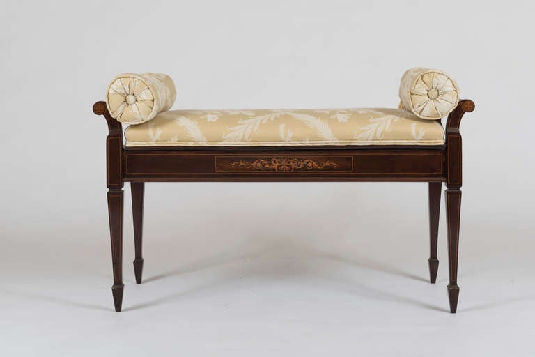 The upholstered seat hinged and opening to a shallow compartment for sheet music, etc.  Inlaid with fruitwood stringing and arabesque decoration.