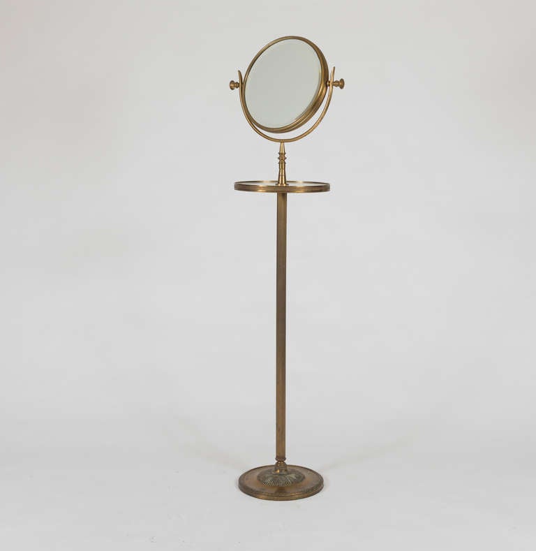 The hinged round mirror on an adjustable support with marble shelf.