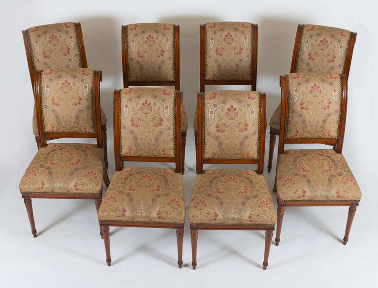 Comprised of 8 side chairs; each with outward scrolling upholstered back and seat; raised on round tapering legs.