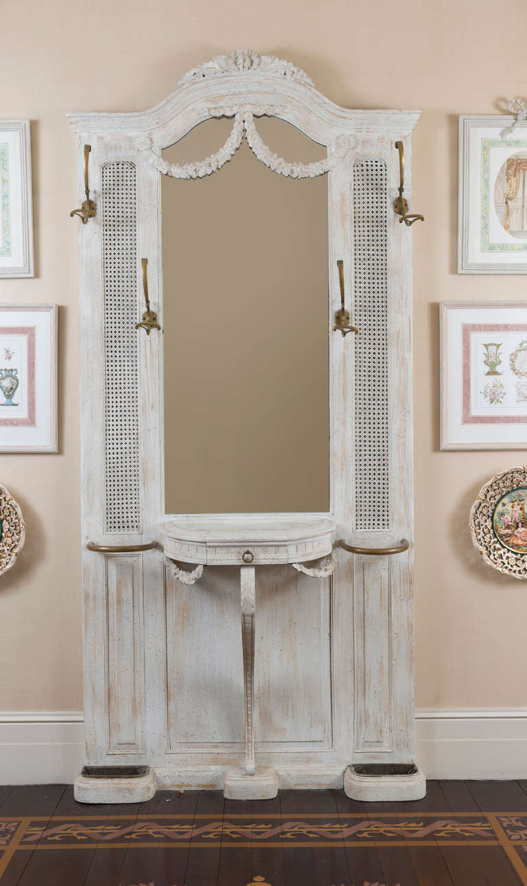 With brass hat hooks and fittings for umbrellas and canes.  The central rectangular mirror over a neoclassical console fitted with a drawer.
