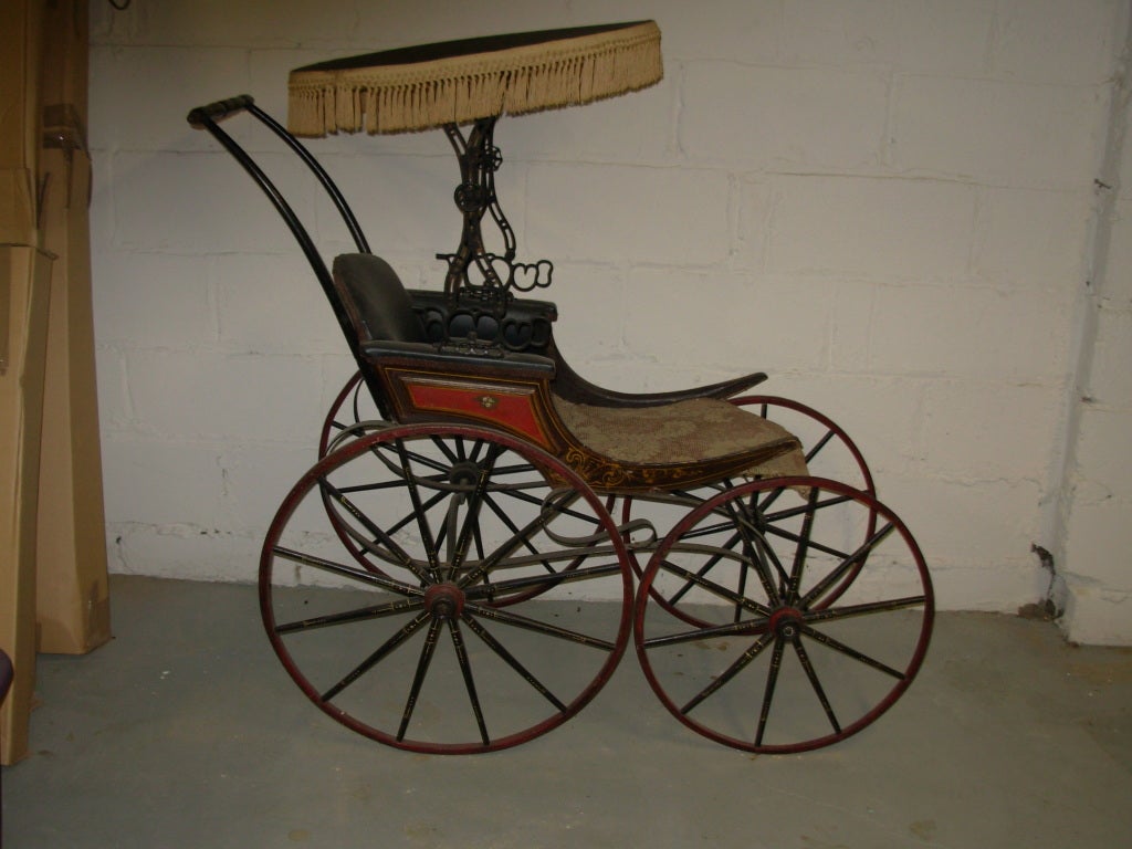 A 19th century child’s carriage. With all original stenciling and paint, in red, black and yellow painted trim. The paint is original and authentic. The seat has a piece of ingrain carpeting
for cover.