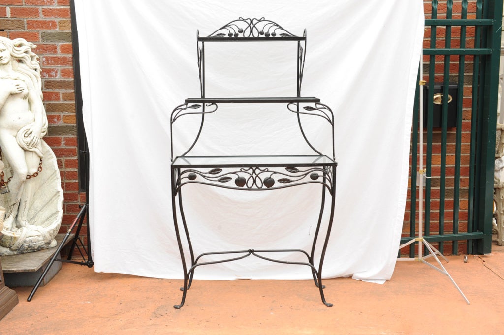 A wrought iron what not or bakers rack by Salterini, carved with fruits, leaves and vines.