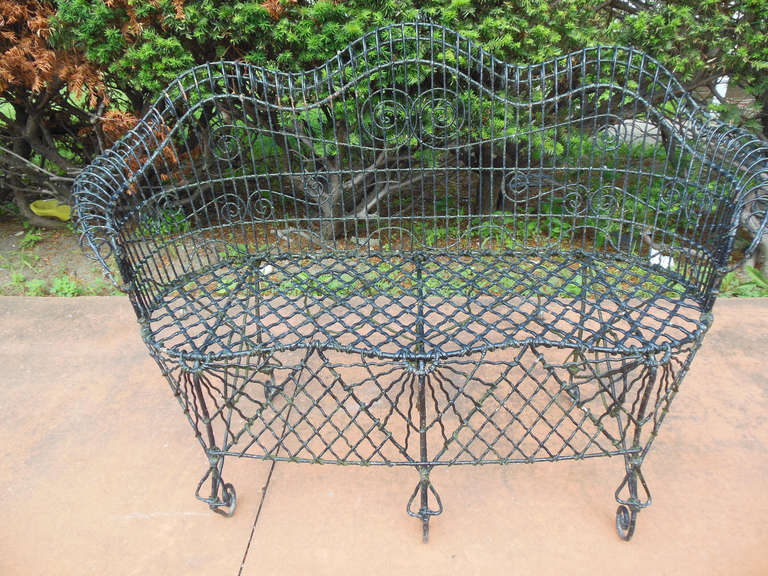 An ornate Black Wire Bench, with some moss in the corners, sturdy
and comfortable, there are no breaks or repairs maintains old painted surface
