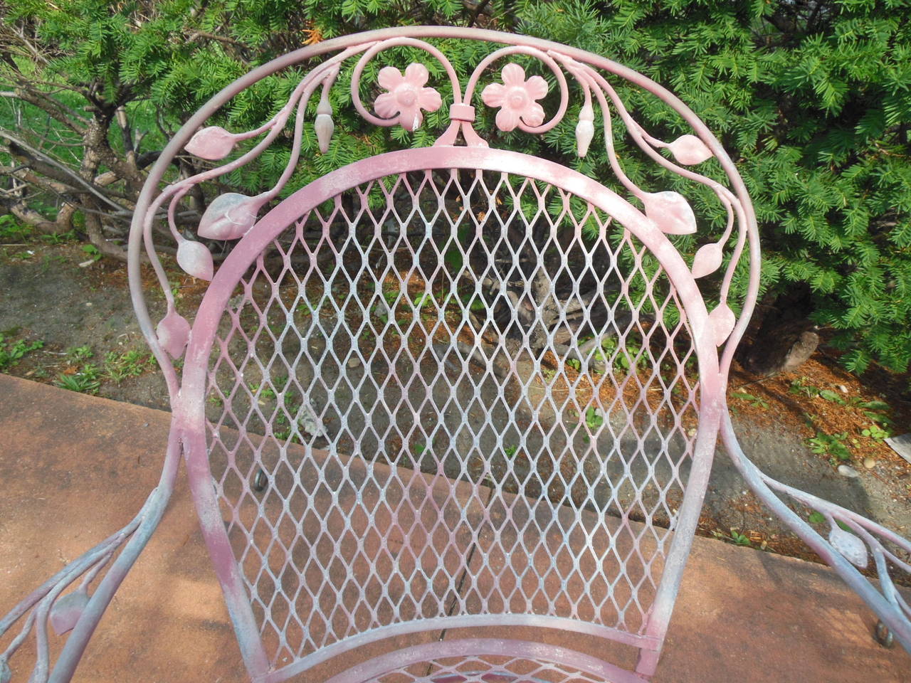 An unusual pair of vintage Salterini wrought iron chairs. The chairs are distinctive in size and style. They do retain some of their original pink paint. Salterini made pieces in several different colors and these are interesting because of their