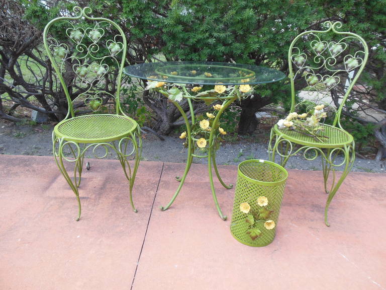 An Italian tole bistro set, that includes a pair of chairs and table with matching waste basket and candle sconce. Several pieces have the metal tag 