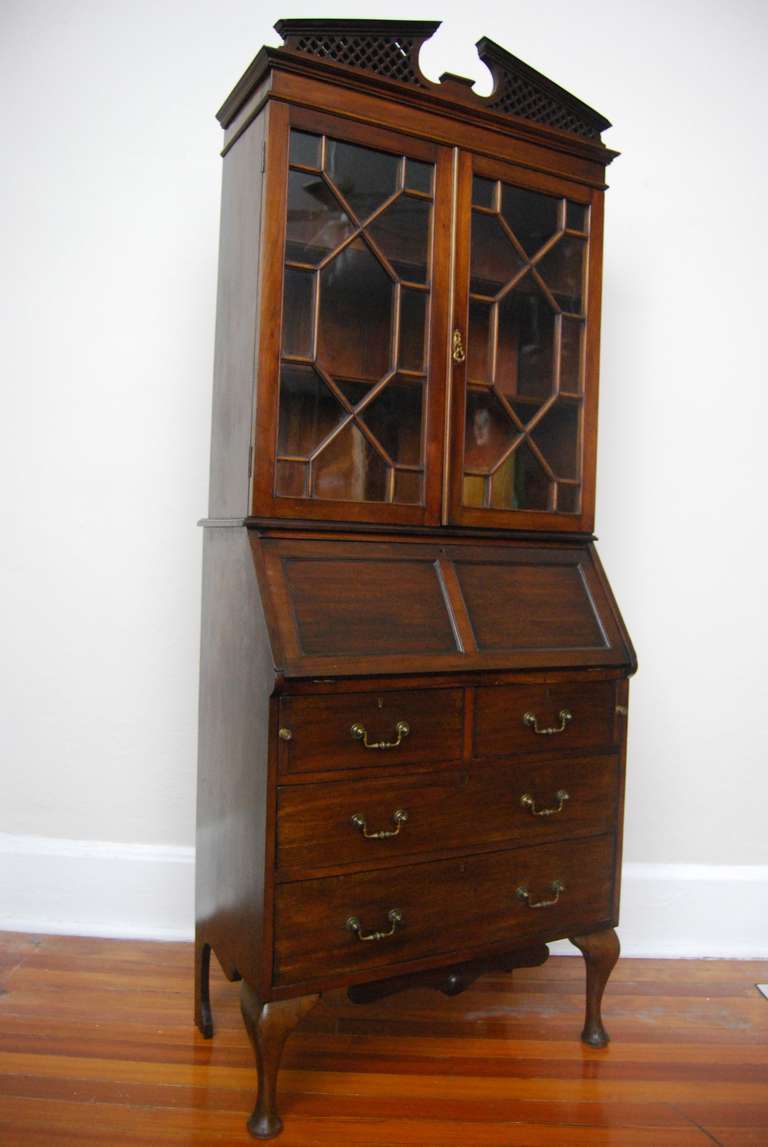 English Mahogany Secretary Bookcase with slant front desk and leather writing surface and fitted interior.  Has original inkwells.  Fretwork pediment. Wonderful petite size.