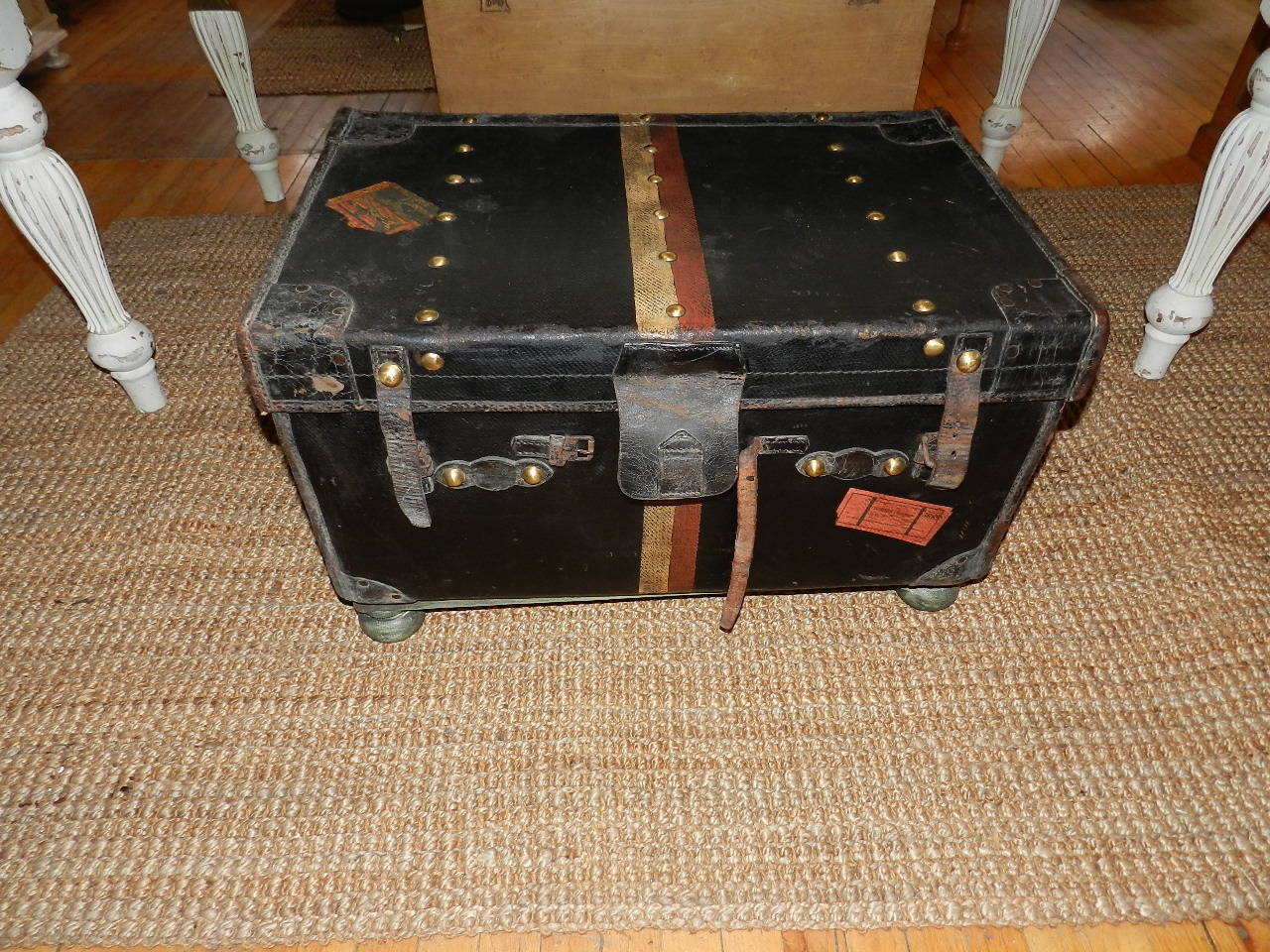 Original steamer trunk from early 1900s with leather strapping and brass lock with wooden stand.