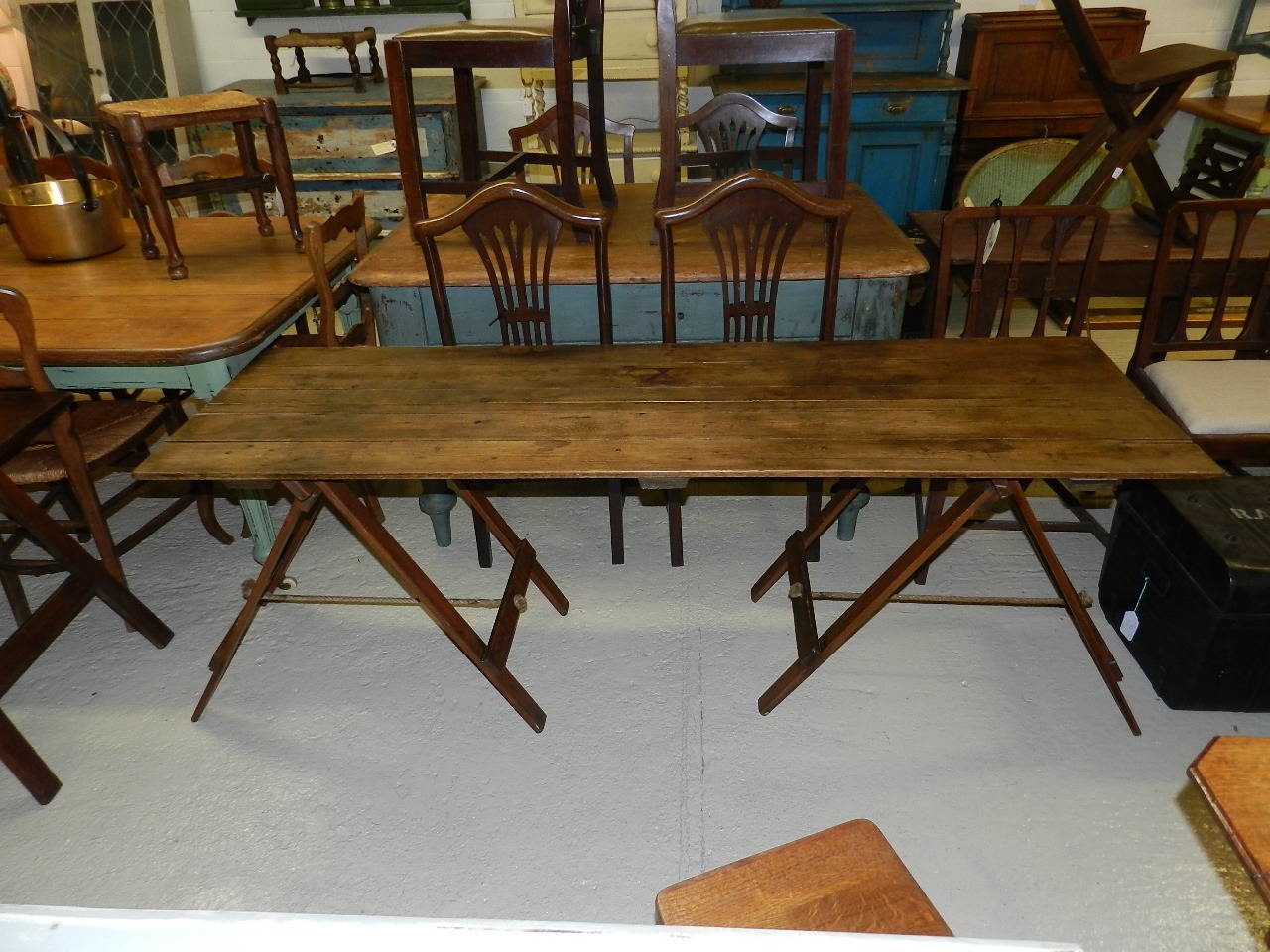 Antique trestle table. Fold out top and two-fold up pine bases with rope stretcher.