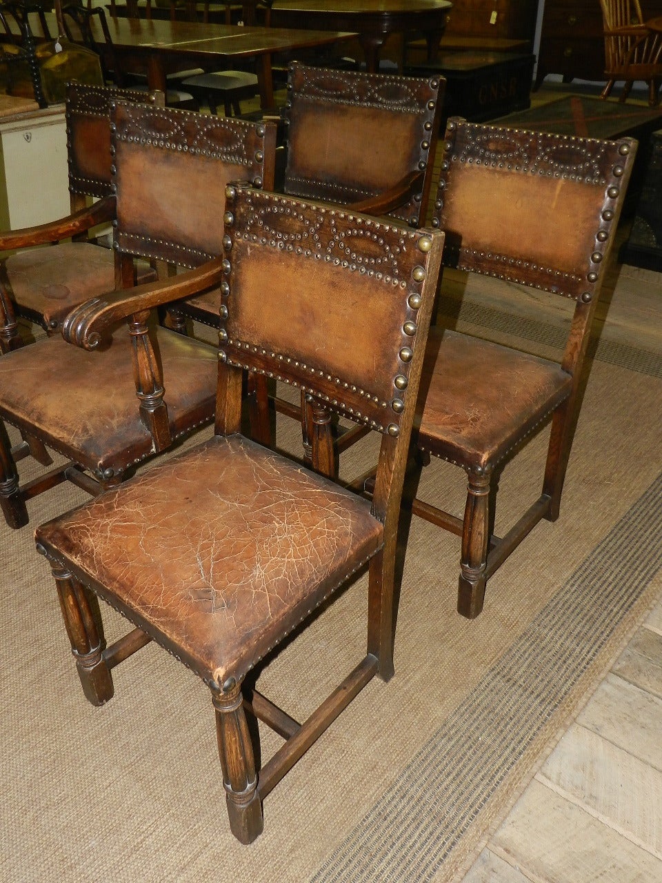 Set of six solid oak chairs with leather upholstery and decorative brass studding. Two arms and four side chairs.