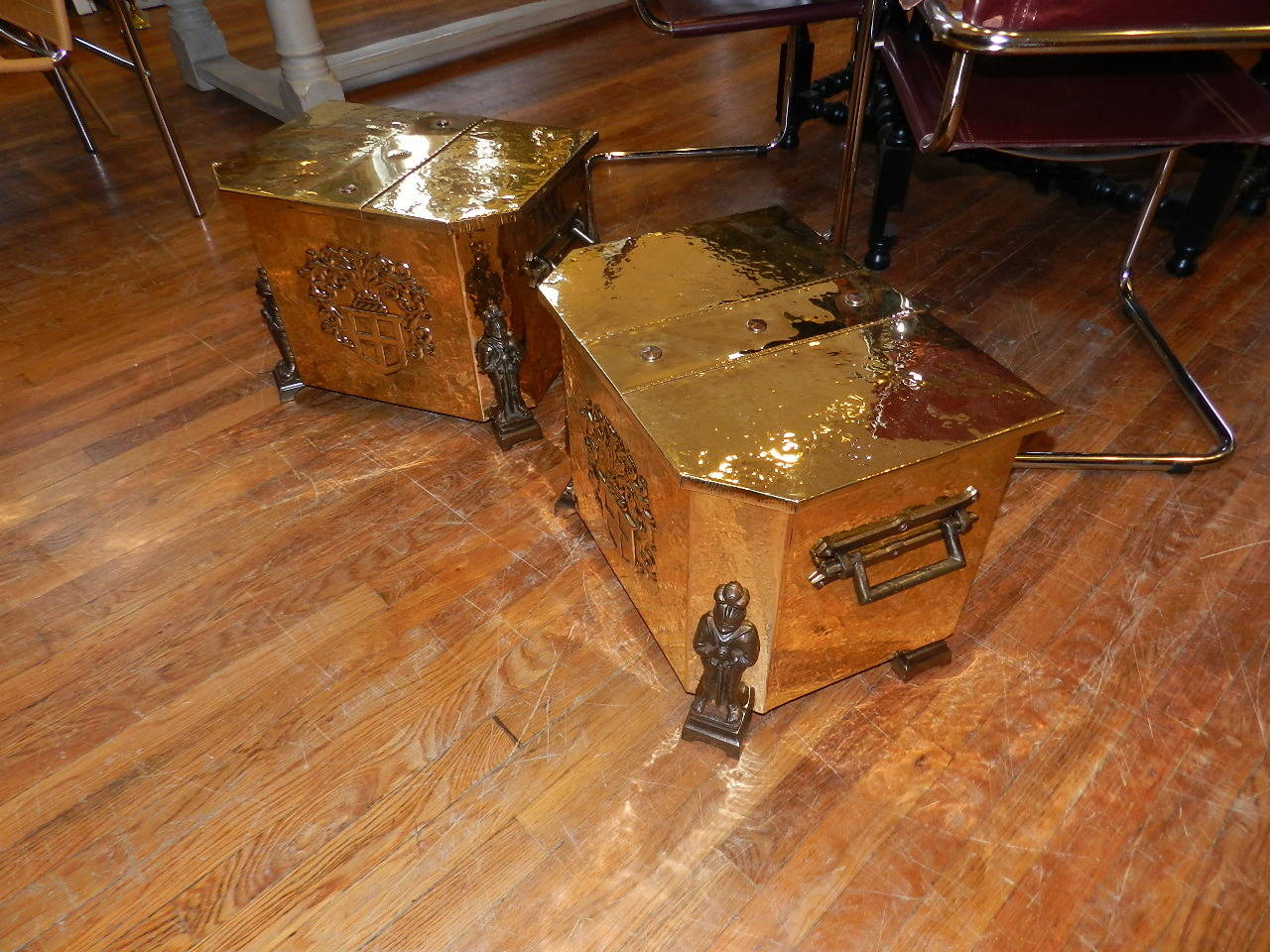 Pair of brass log boxes with impressed coat of arms, iron decorative corner posts and iron carry handles.