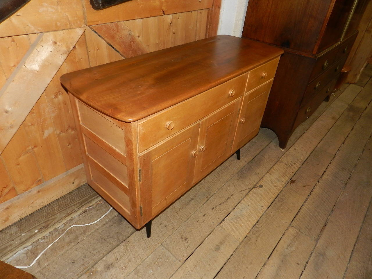 Teak sideboard with panelled sides made by Ercol. 3 panelled doors and 2 drawers supported upon tuned frame.