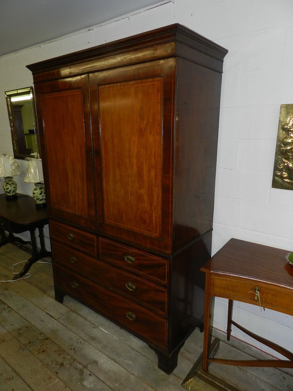 Mahogany linen press. The two crossbanded and inlaid panel doors have a brass door bead. The base has dovetailed inlaid drawers with antique brass handles and bracket feet.