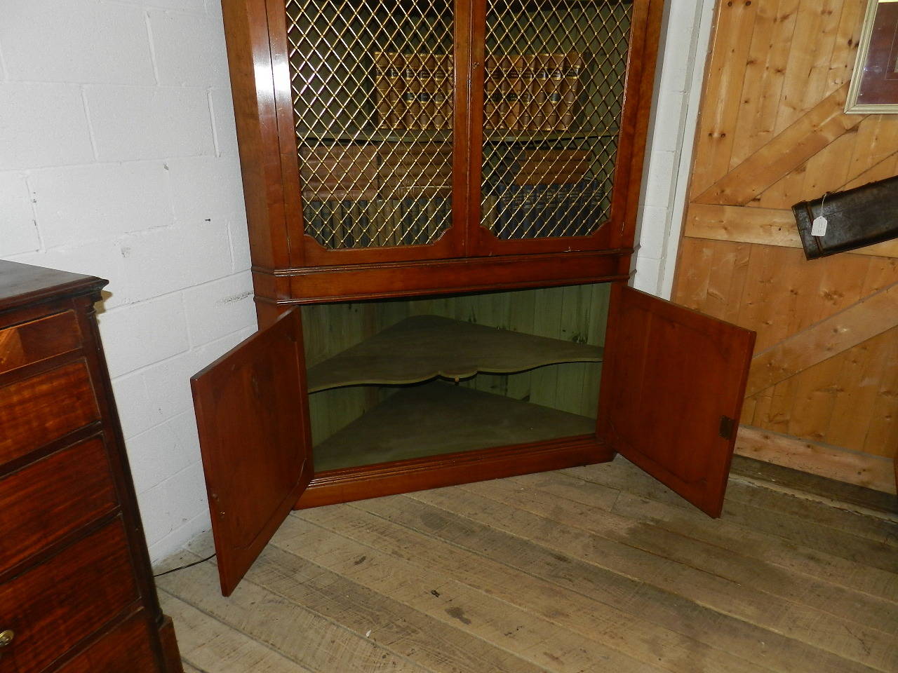 Handmade solid cherry corner cupboard. The base section has two paneled doors and the upper has panels of brass grille. The upper section has two scallop shaped shelves and would house a 50' inch widescreen T.V. (with slight adaption). It is