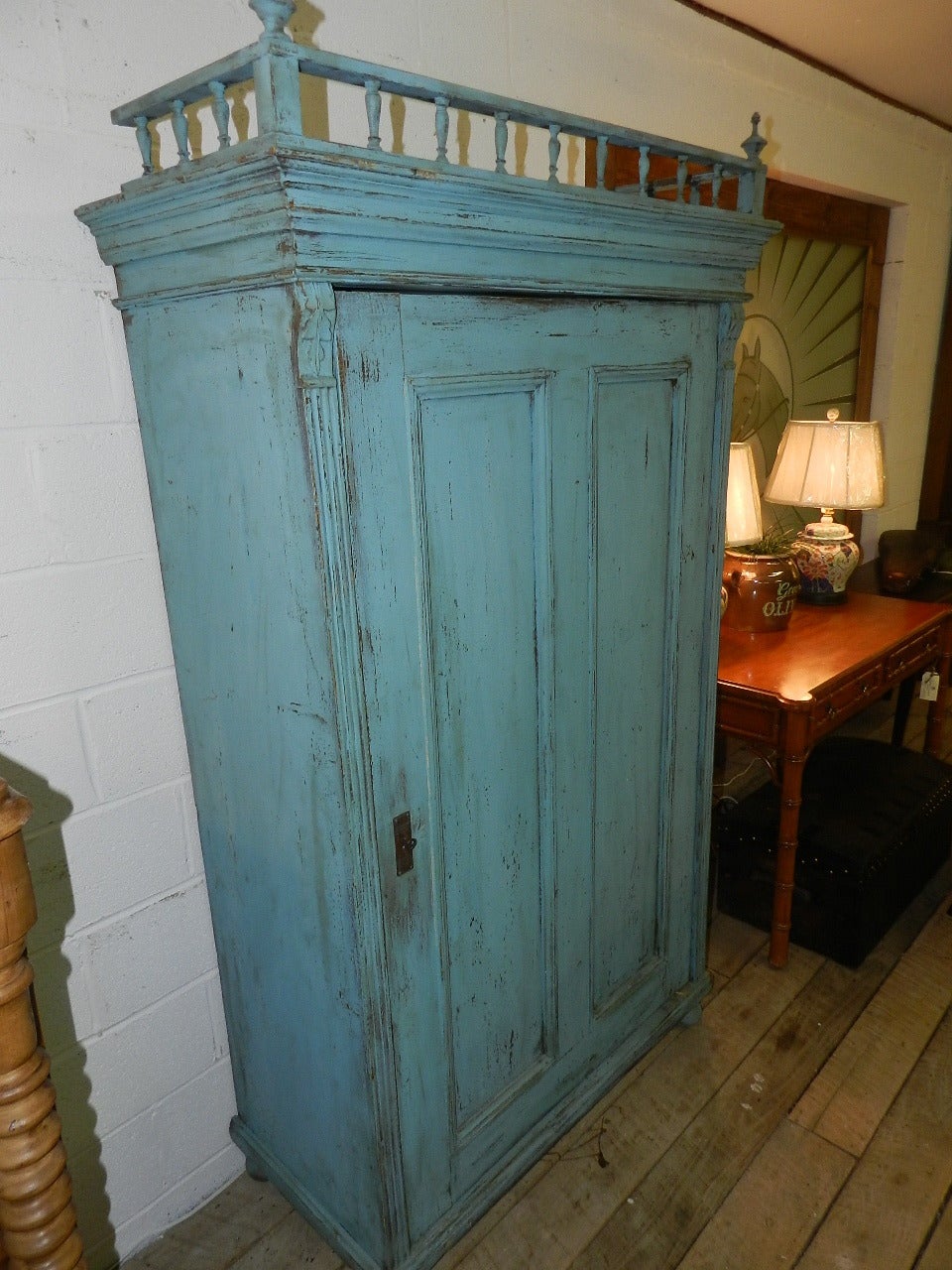 Antique pine armoire with original blue paint. The interior has three removable shelves. The single paneled door still has the original lock, key and escutcheon.