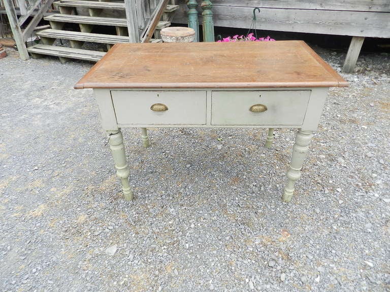 Having a pine top with great patina, this work table or island has its original brass cup handles.  A French gray paint compliments the pine top.  