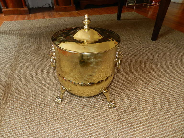 Solid brass coal or log bucket with lid and metal liner bucket. The brass  bucket has lion's head handles and paw feet. The lid has a turned finial type handle. .