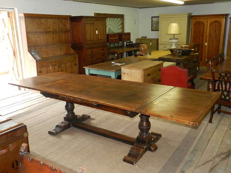 Large oak draw leaf dining table on a trestle base.