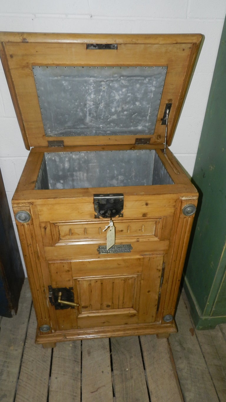 This original antique pine ice chest from Budapest, Hungary,  retains beautiful hardware .  Behind the  brass handled front opening door is a tin lined space ideal for cooling ice or drinks on a hot summer's day.  The top is hinged and a stay
